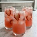 Strawberry soda in ice-filled glasses with fresh strawberry slices, perfect for a refreshing homemade summer drink recipe.