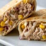 Crispy tuna melt wrap cut in half with creamy tuna, corn, and melted cheese filling.