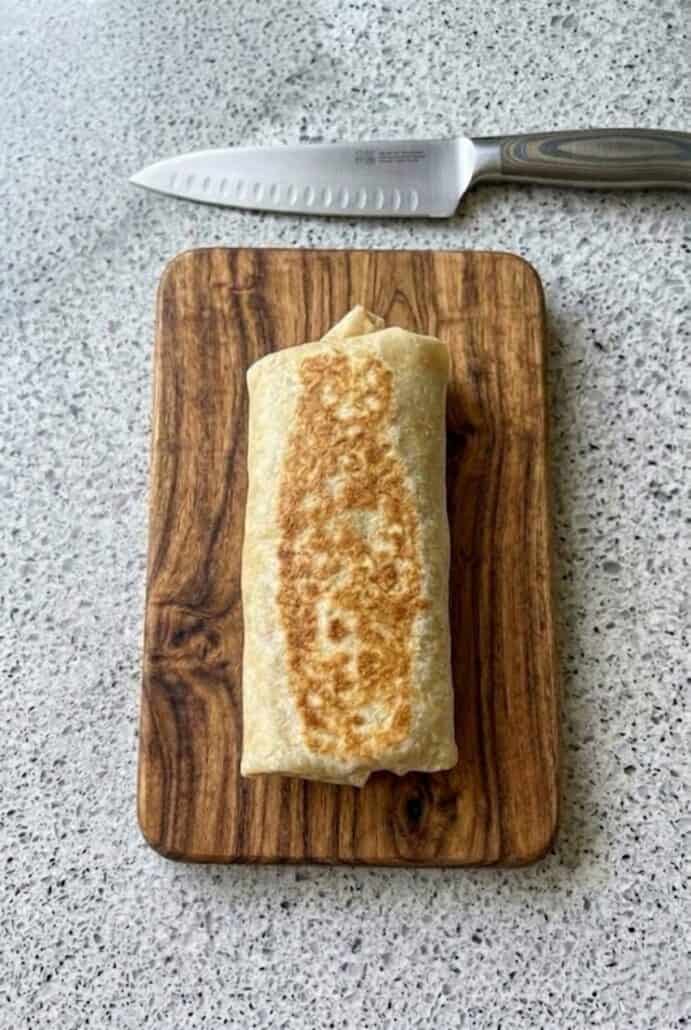 Golden brown tuna melt wrap on a cutting board, ready to serve.