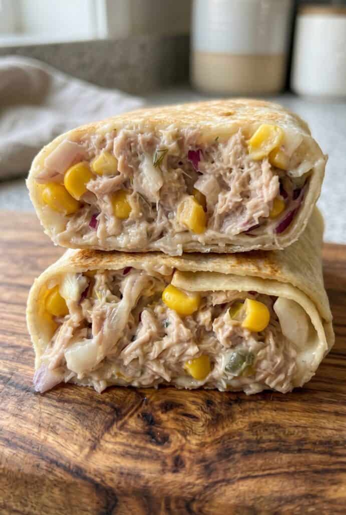 Stacked tuna melt wrap halves with creamy tuna, corn, red onion, and melted cheese filling.