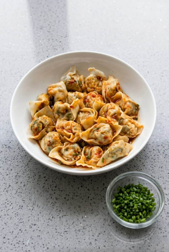 Plate of vegan tofu and chive wontons topped with chili oil.