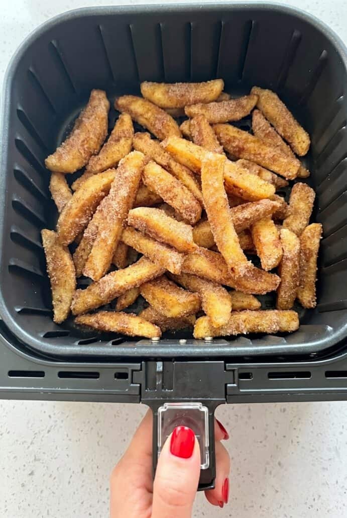Air fryer apple fries finished cooking in the basket until golden and crispy.