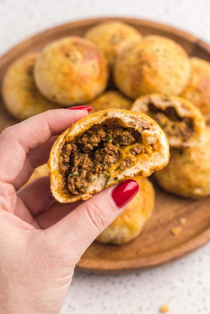 Hand holding a halved air fryer taco bomb filled with seasoned beef and melted cheese.