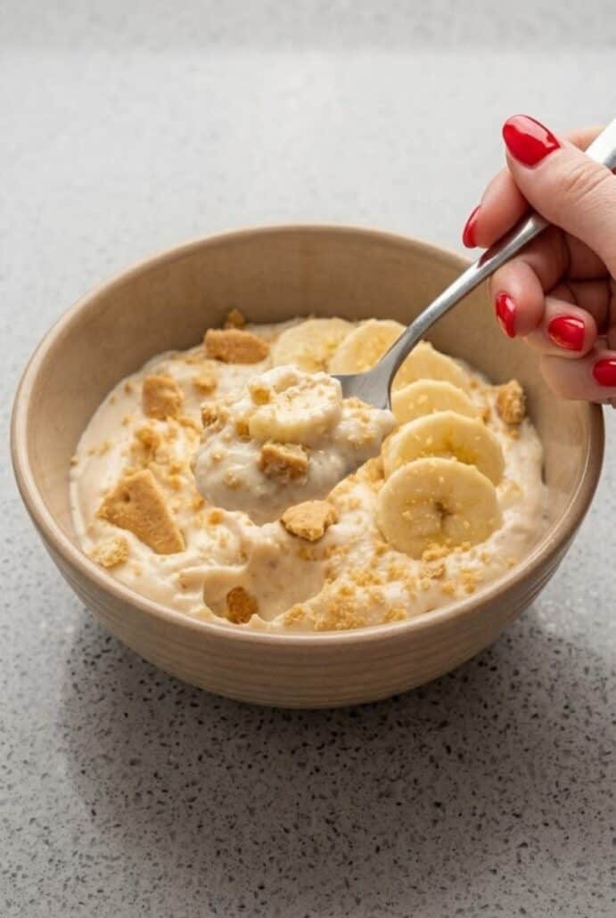 Banana Pudding Yogurt with a spoonful of creamy yogurt, banana slices, and graham cracker crumbs.