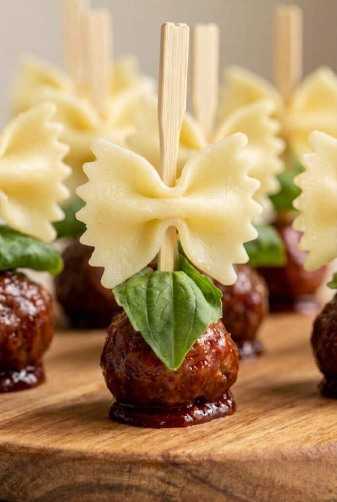 Close-up of bowtie pasta and cocktail meatball skewer with basil for an easy bite-sized appetizer.
