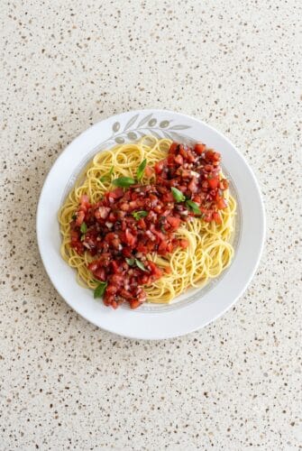 Bruschetta Pasta Salad Recipe With Fresh Tomatoes And Basil Bruschetta pasta salad with spaghetti, fresh tomatoes, basil, and balsamic glaze on a white plate.