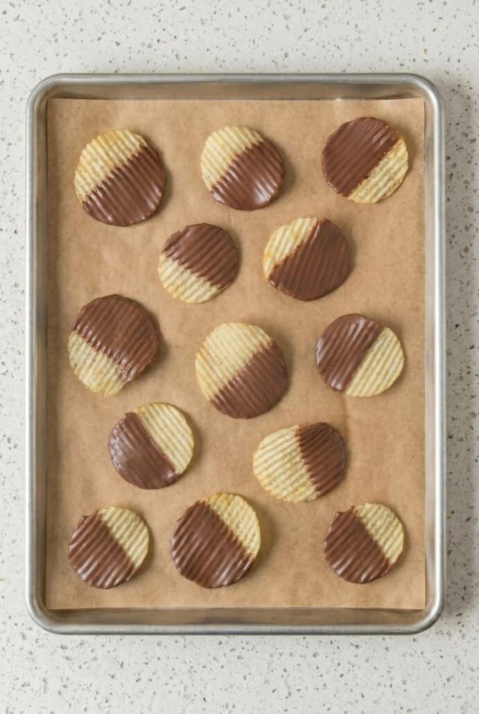 Chocolate dipped potato chips setting on parchment paper for an easy homemade snack.