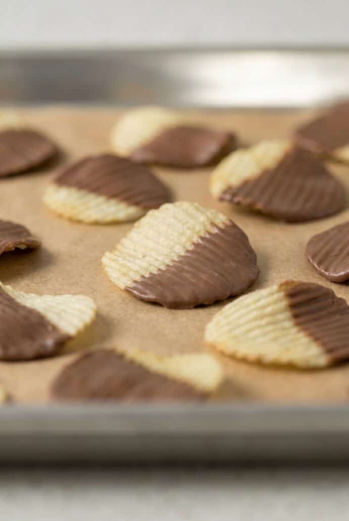 Chocolate covered potato chips arranged on parchment paper while the chocolate sets.