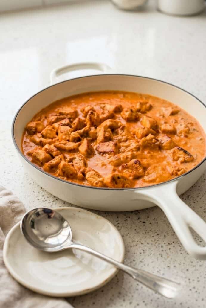 Creamy coconut chicken simmering in a skillet for coconut chicken rice bowls.