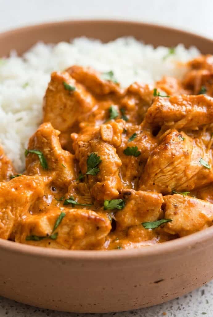 Close-up of creamy coconut chicken with fresh cilantro served over white rice.