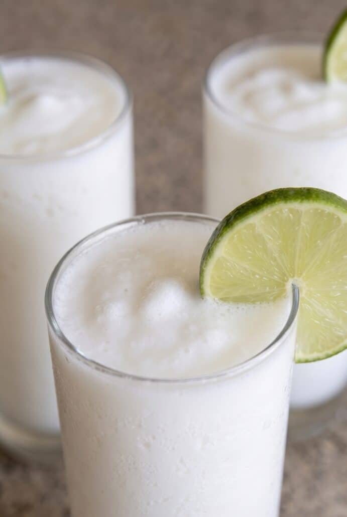 Close-up of frosty Colombian coconut limeade with fresh lime garnish on the glass.