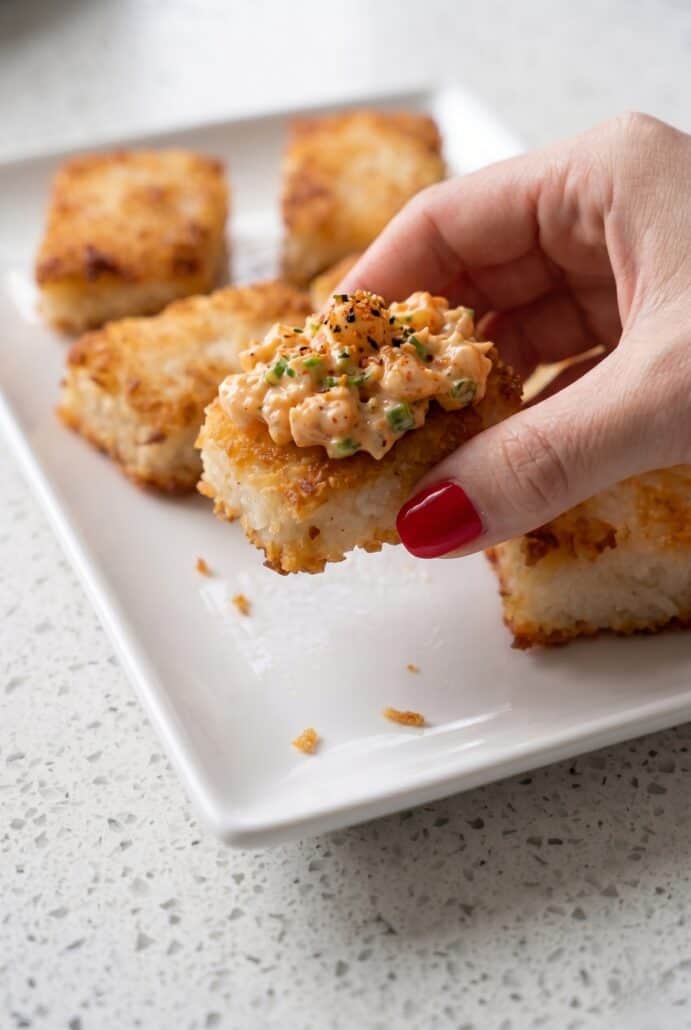 Hand holding a golden crispy rice square to show the crunchy texture of this easy appetizer recipe.