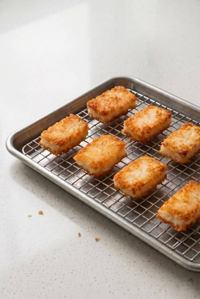 Crispy rice squares cooling on a wire rack after pan frying for appetizer recipe.