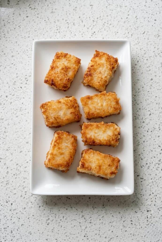 Golden crispy rice squares served on a white plate for an easy appetizer or snack recipe.