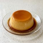 Eggless caramel pudding with golden caramel sauce on a plate.