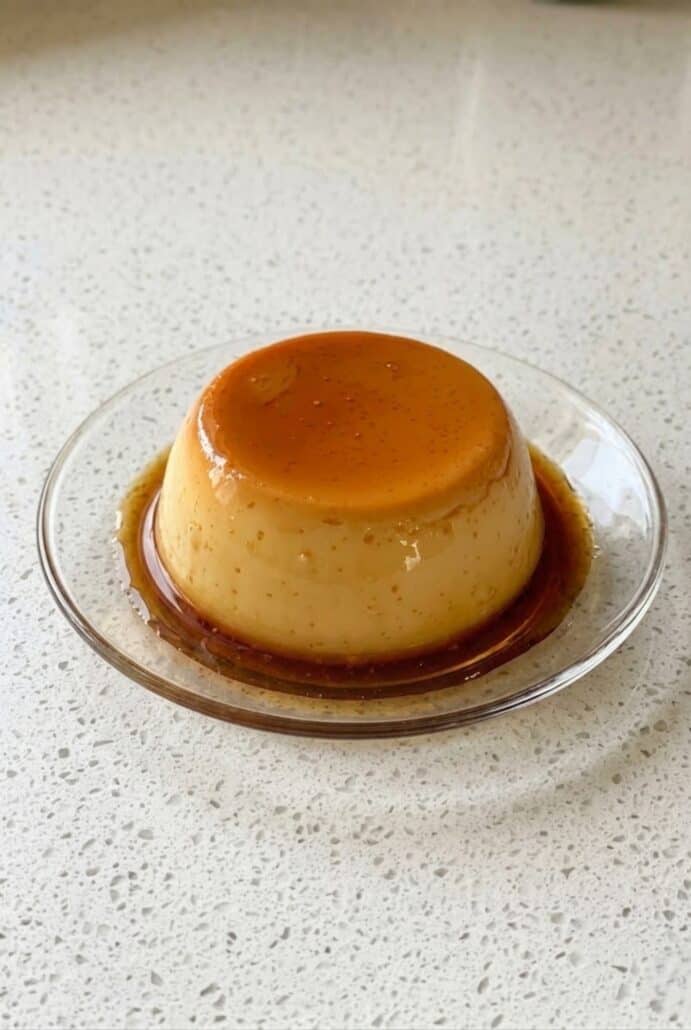 Eggless caramel pudding with golden caramel sauce on a plate.