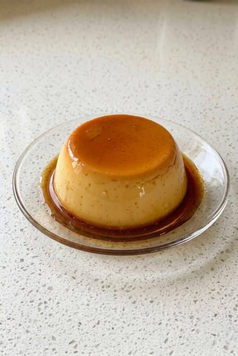 Eggless caramel pudding with golden caramel sauce on a plate.