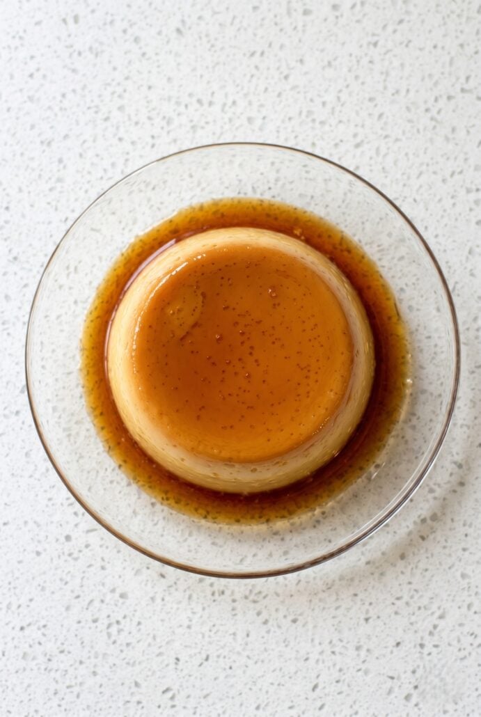 Top view of eggless caramel pudding with caramel sauce on a glass plate.