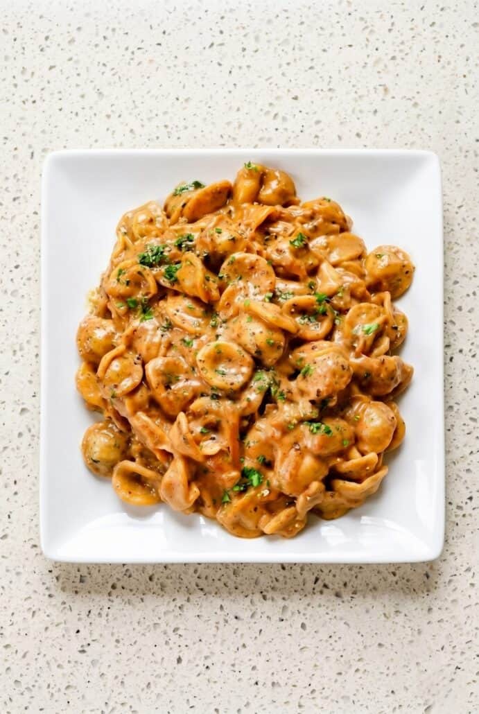 Creamy French Onion Pasta with orecchiette, caramelized onions, Gruyere, Parmesan, and fresh parsley on a serving platter.