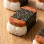 Hawaiian Spam musubi with caramelized Spam, sushi rice, and nori wrap on a wooden board.