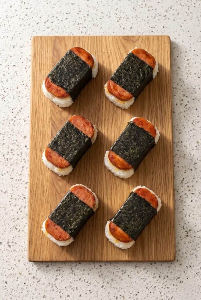 Homemade Hawaiian Spam musubi arranged on a wooden board, ready to serve as an easy snack or lunch.