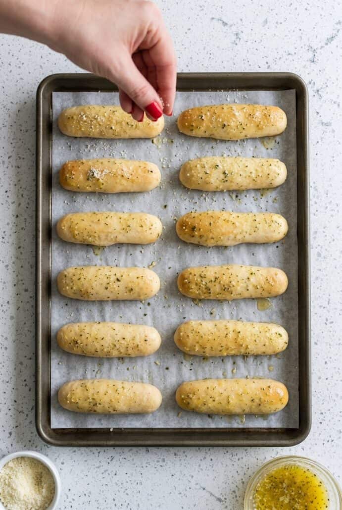 Homemade breadsticks baking on a parchment-lined sheet pan until golden and fluffy.