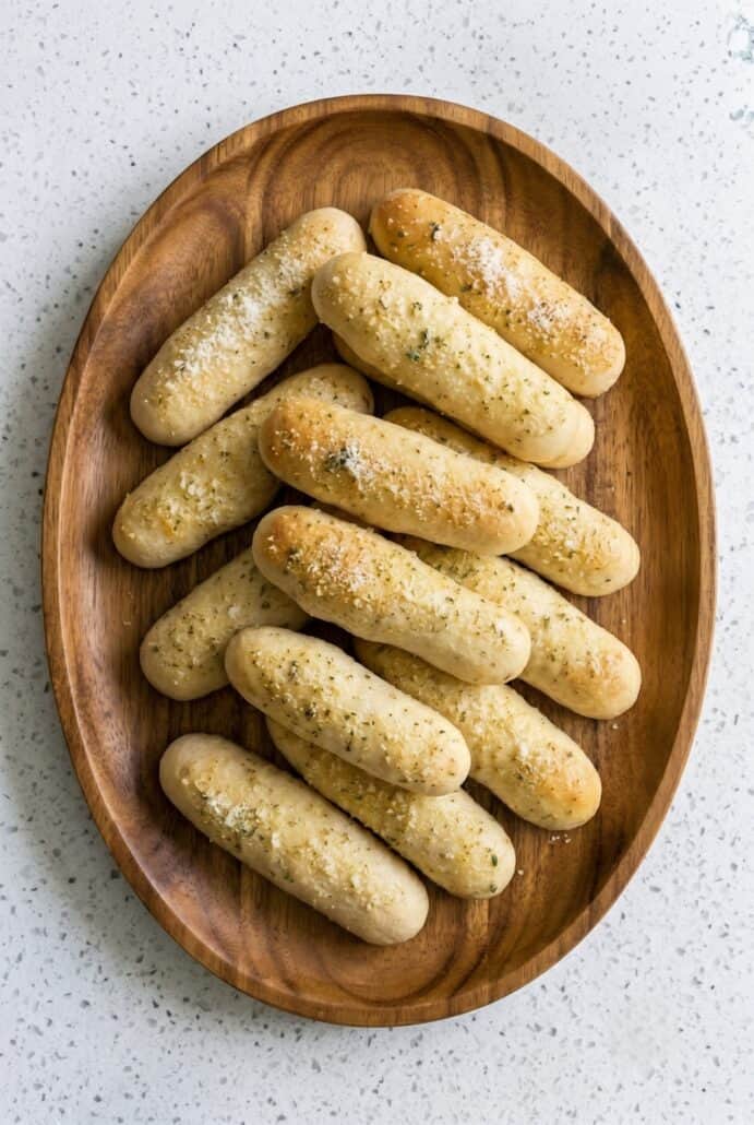 Homemade garlic breadsticks served warm on a wooden platter.