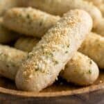 Homemade breadsticks topped with garlic butter, Parmesan cheese, and herbs.