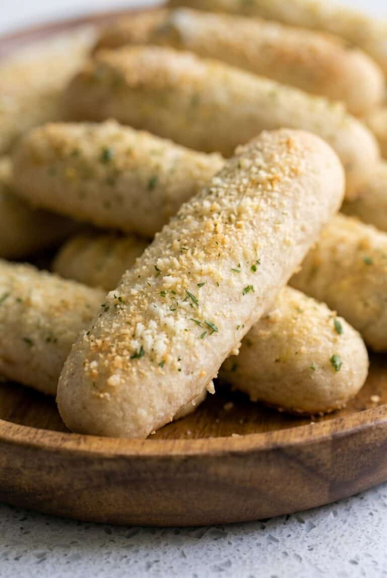 Homemade breadsticks topped with garlic butter, Parmesan cheese, and herbs.