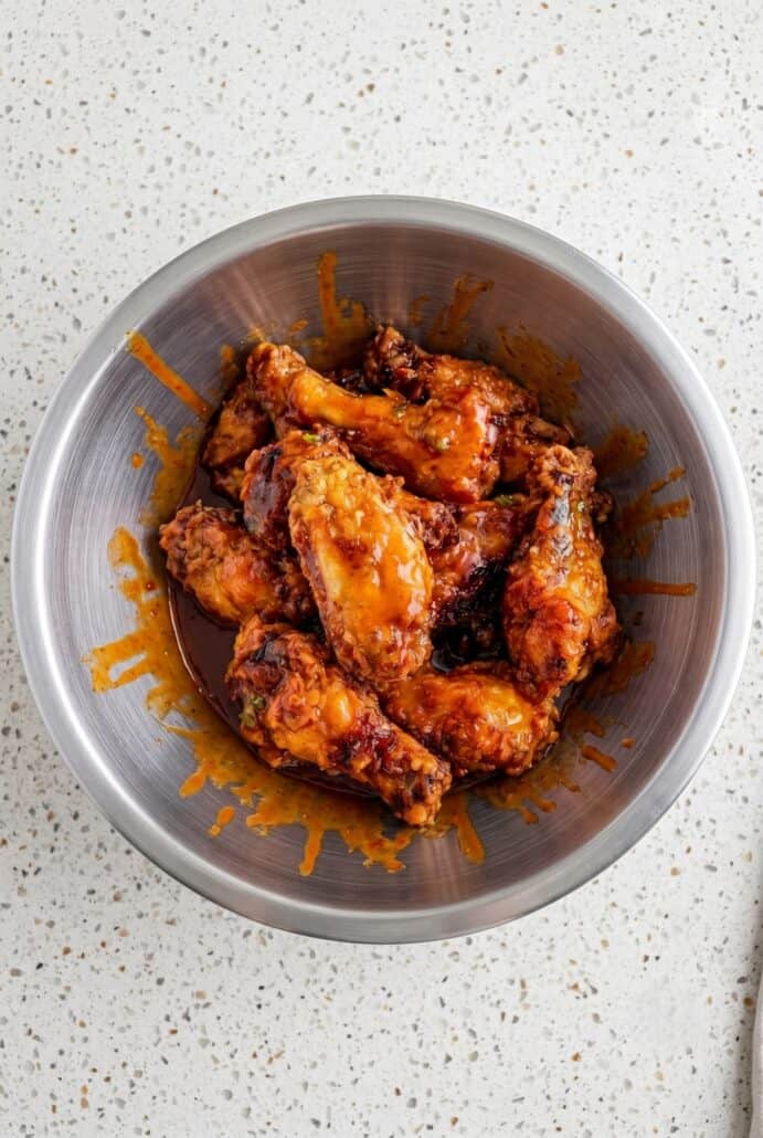Crispy Hot Honey Peach Wings served in a bowl and coated in a sticky sweet and spicy peach glaze.