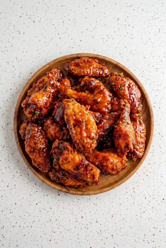 Bowl of crispy Hot Honey Peach Wings coated in a glossy sweet and spicy peach glaze.