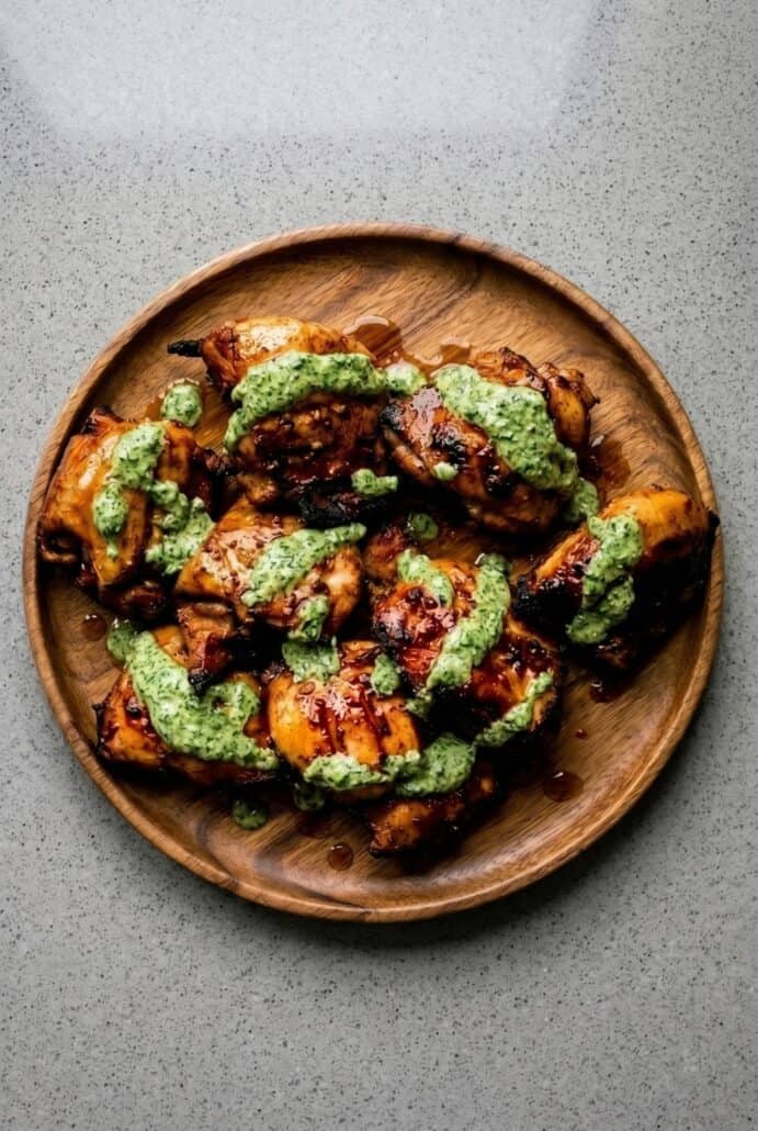 Grilled Peruvian chicken topped with creamy green sauce on a serving plate.