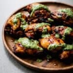 Grilled Peruvian chicken with creamy green sauce on a plate.