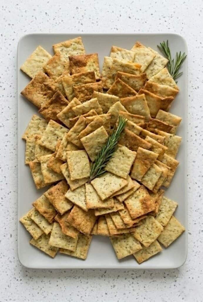 Homemade rosemary sea salt crackers piled on a plate.