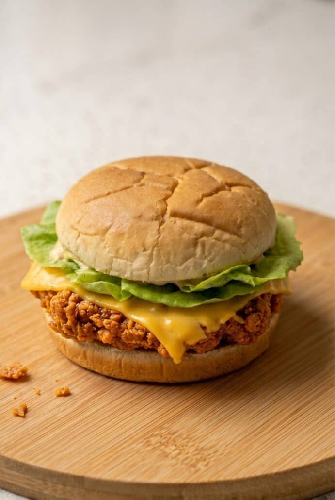 Spicy fried chicken burger with cheese, lettuce, and spicy mayo on a toasted bun.