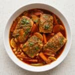 Bowl of Spicy Moroccan fish with salmon, vegetables, cilantro, and rich paprika sauce.