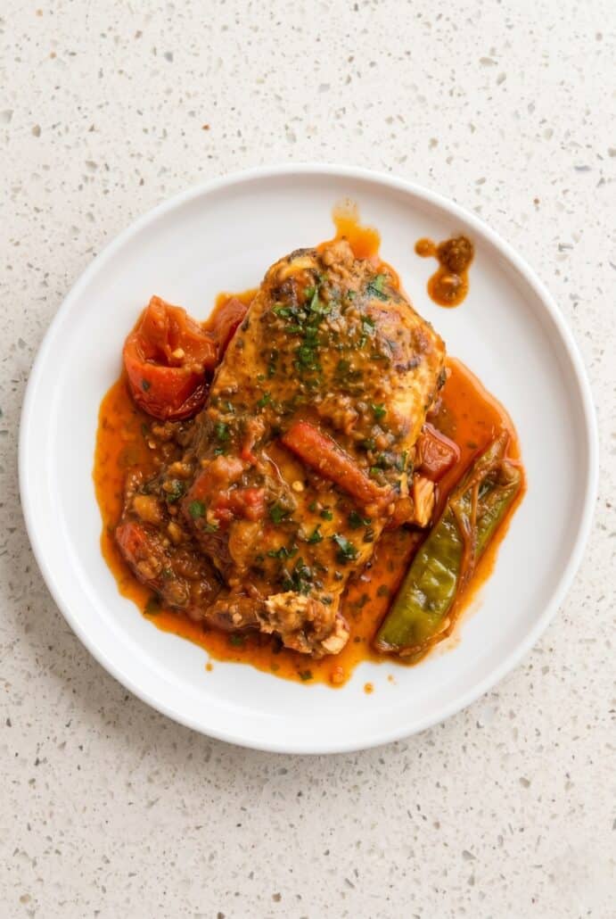 Plate of Spicy Moroccan fish topped with cilantro and served with carrots and peppers in paprika sauce.