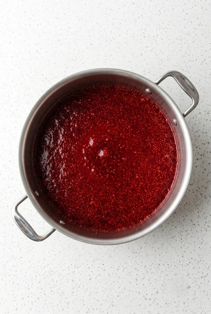 Strawberry jam cooking in a pot on the stove for homemade strawberry jam recipe.