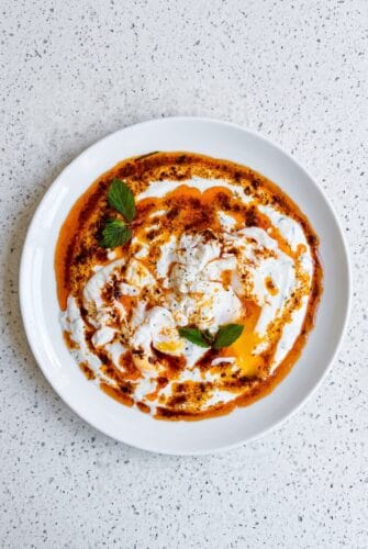 Turkish Eggs (Cilbir) Recipe With Creamy Yogurt And Spiced Butter Turkish eggs with poached eggs, garlic yogurt, fresh herbs, and spiced butter sauce.