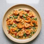 Creamy Tuscan shrimp with spinach, sun-dried tomatoes, and artichokes in a skillet sauce.