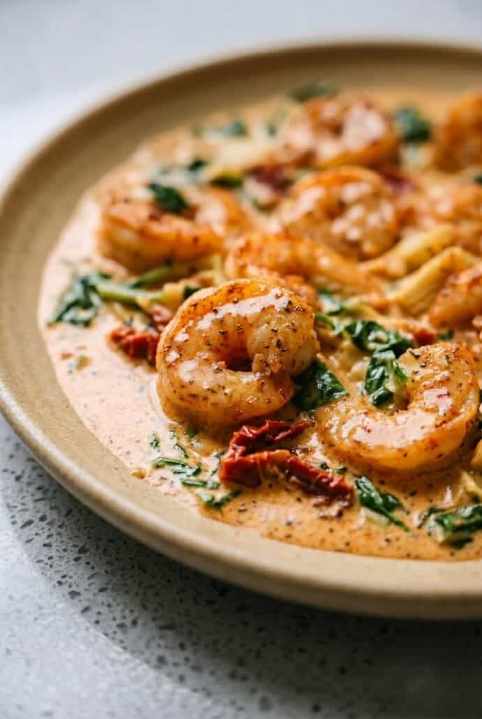 Close-up of creamy Tuscan shrimp with spinach and sun-dried tomatoes in a rich garlic sauce.