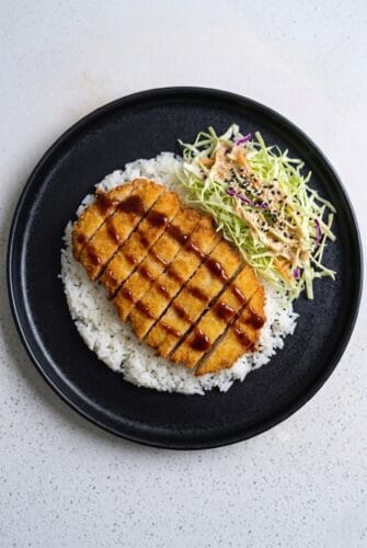 Chicken Katsu served over rice with colorful cabbage slaw and tonkatsu sauce.