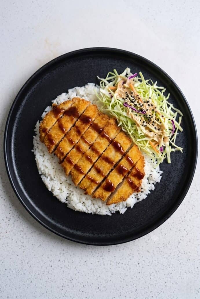 Chicken Katsu served over rice with colorful cabbage slaw and tonkatsu sauce.