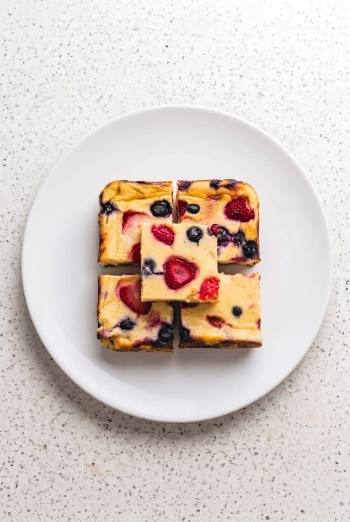 Four berry baked yogurt squares served on a white plate for breakfast or a snack.