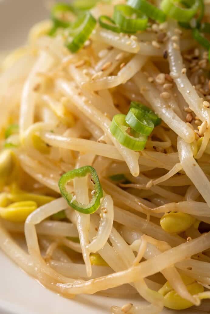 Close-up of Korean bean sprout salad with sesame seeds and sliced green onions.