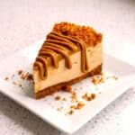 Slice of creamy Biscoff cheesecake with melted Biscoff spread drizzle and crushed Biscoff topping.