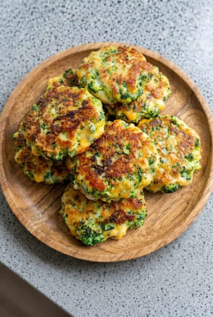 Broccoli cheese patties served on a wooden plate, perfect as a crispy vegetarian appetizer or side dish.