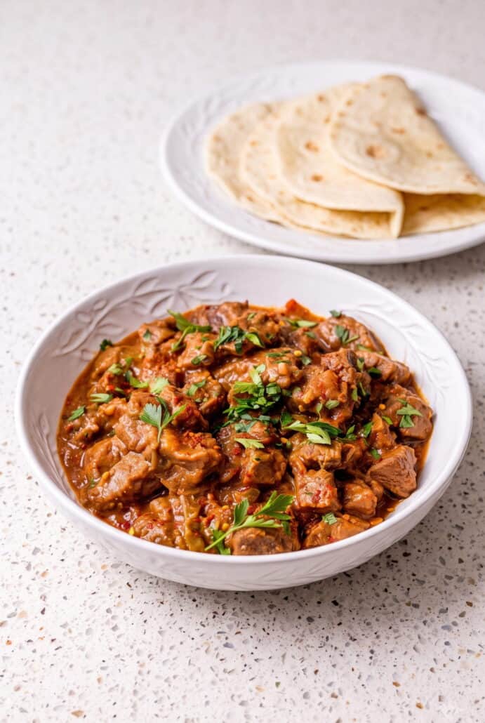 Carne guisada topped with cilantro and served with warm flour tortillas.