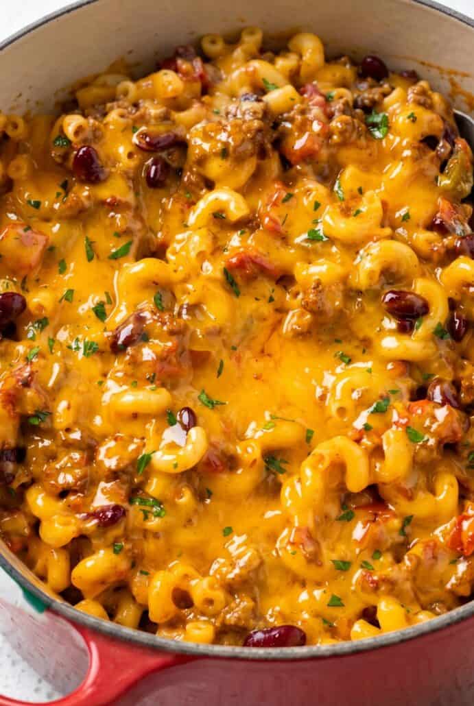 Close-up of creamy chili mac with ground beef, tender macaroni, melted cheddar, and parsley.