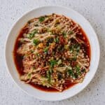 Enoki mushrooms topped with garlic and scallion sauce, served as an easy vegan Asian side dish.